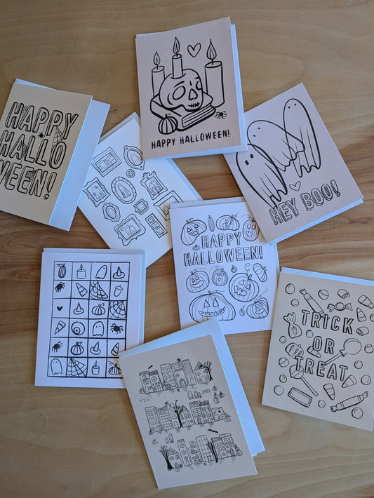 Set of Halloween-themed cards with black line art on a wooden surface
