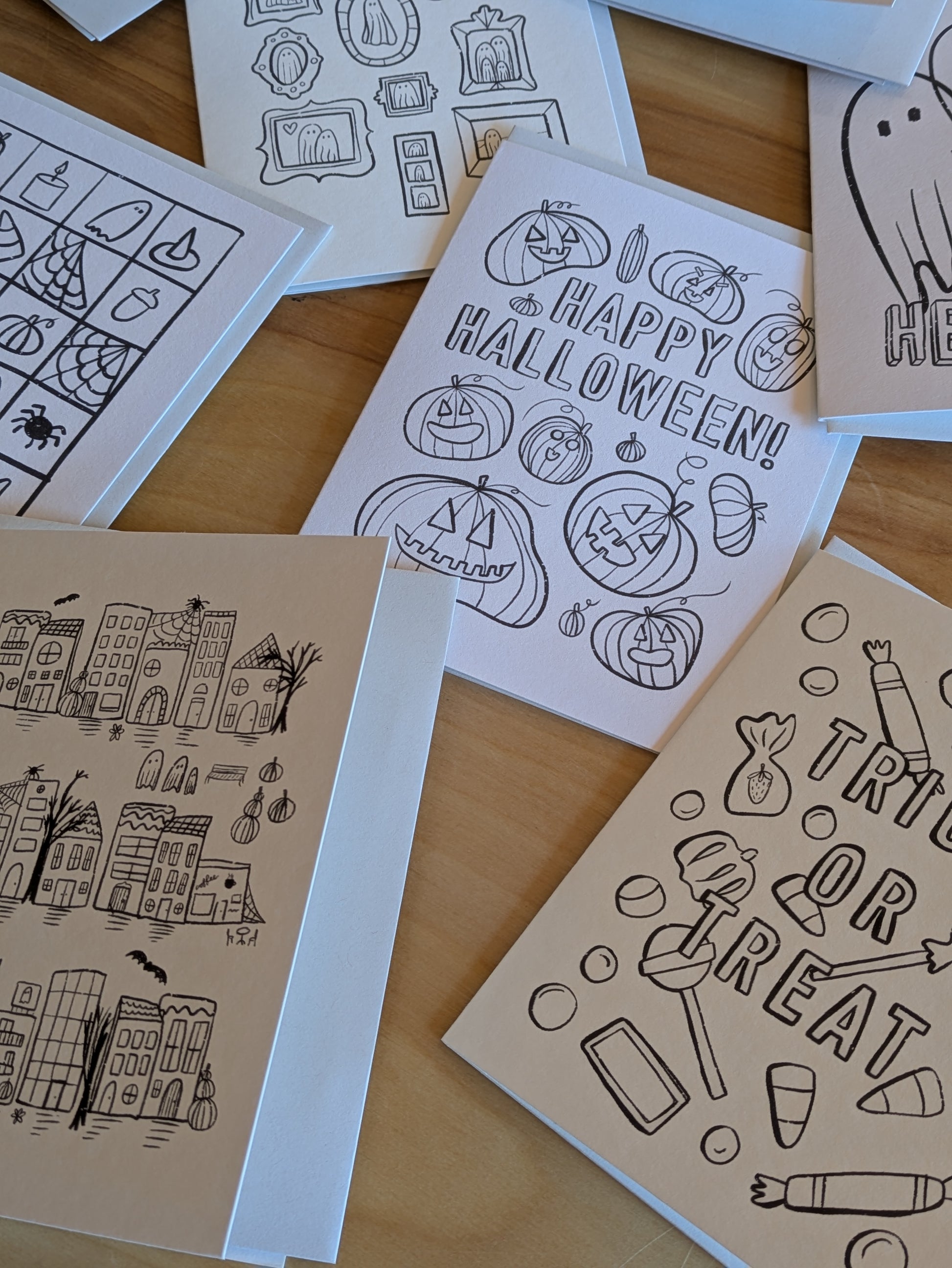 Collection of Halloween-themed coloring pages on a wooden desk
